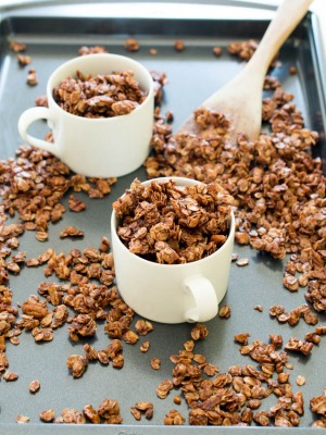 chocolate granola recipe in white cups on sheet pan with loose granola