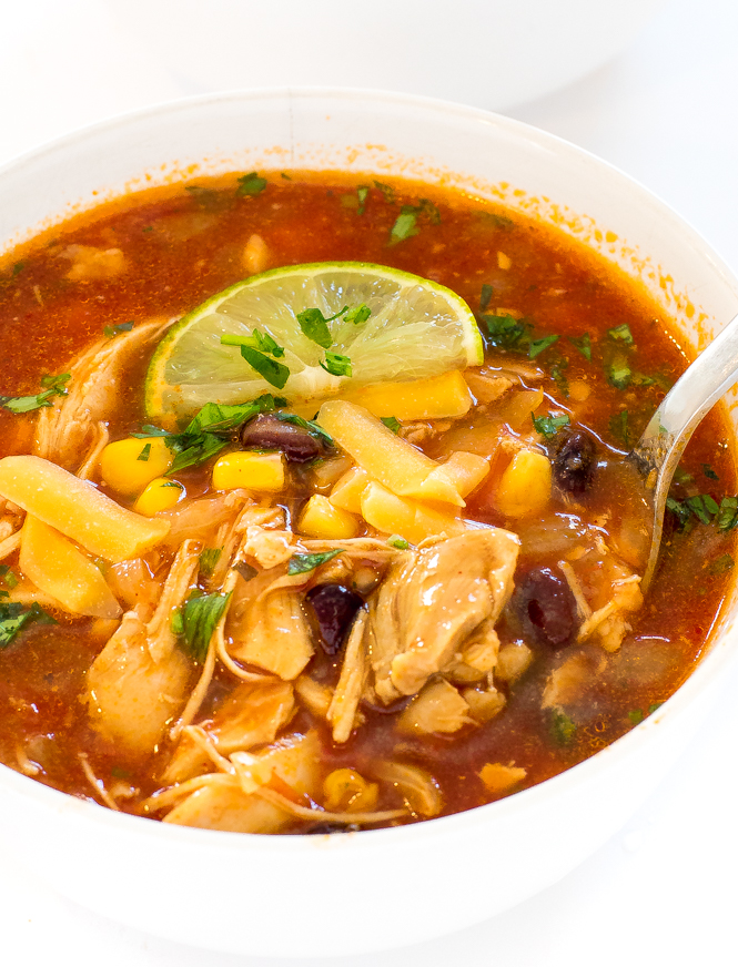 Easy 20 Minute Chicken Tortilla Soup in white bowl chicken tortilla soup topped with cilantro and a lime wedge