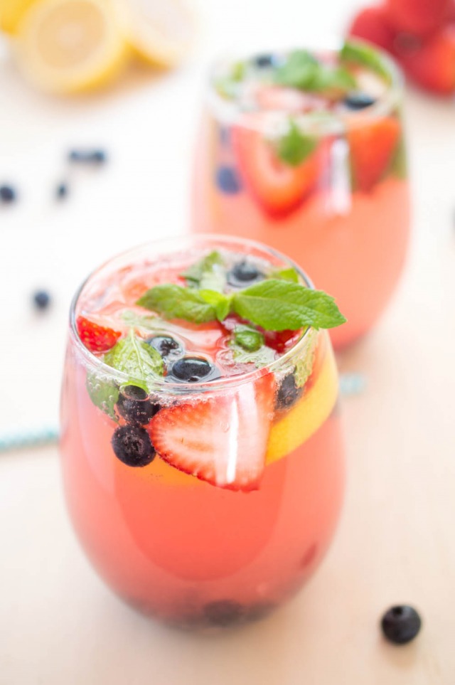 A closeup of two glasses filled with this spiked berry lemonade recipe garnished with berries and fresh mint | chefsavvy.com
