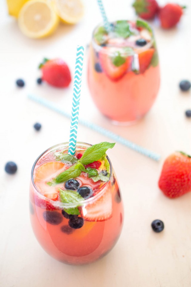 A closeup of two glasses filled with this spiked berry lemonade recipe garnished with berries and fresh mint | chefsavvy.com
