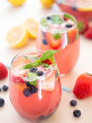 A closeup of two glasses filled with this spiked berry lemonade recipe garnished with berries and fresh mint | chefsavvy.com