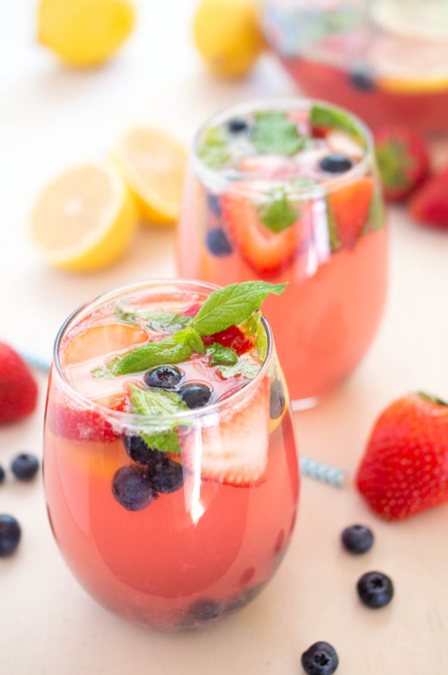 A closeup of two glasses filled with this spiked berry lemonade recipe garnished with berries and fresh mint | chefsavvy.com