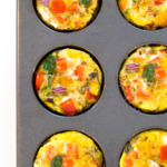 an overhead view of these easy egg muffin cups in a muffin tin with chopped peppers, onions, and spinach