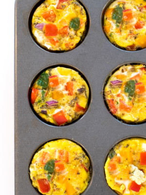 an overhead view of these easy egg muffin cups in a muffin tin with chopped peppers, onions, and spinach