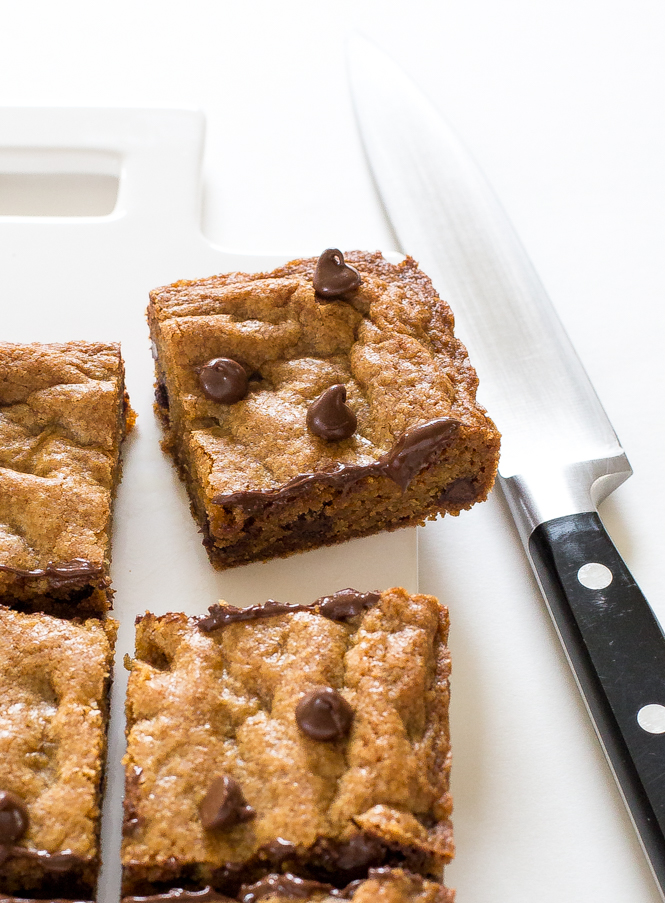 Browned Butter Chocolate Chip Blondies cut into square on white cutting board next to knife
