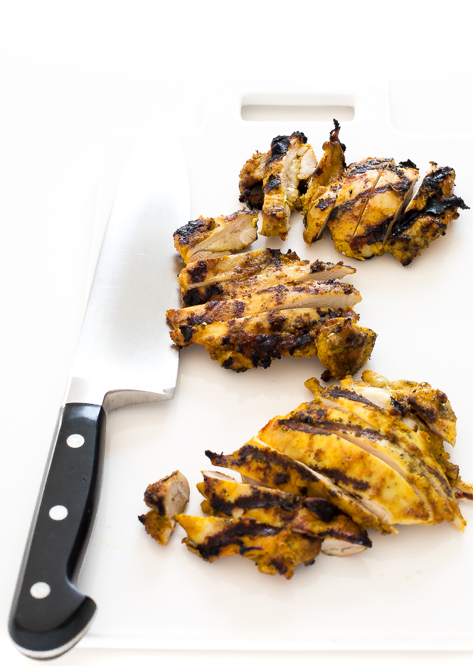 slicing chicken thighs on white cutting board