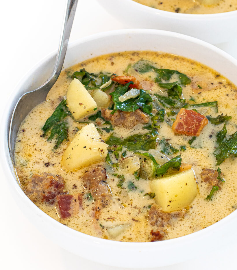 Zuppa toscana soup in a white bowl with a silver spoon. 