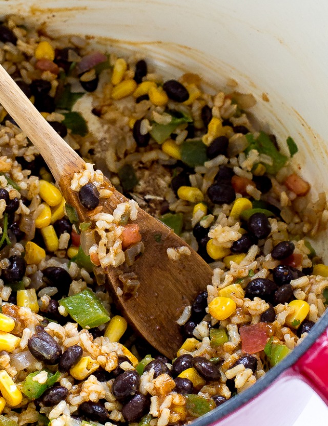 Stirring enchilada rice with a wooden spoon.