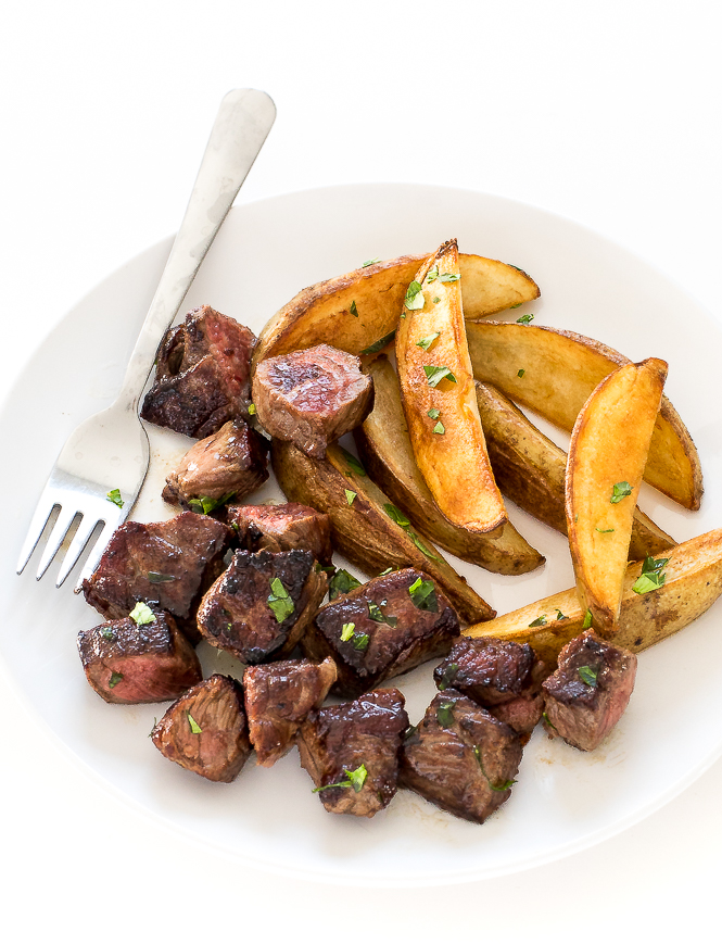 Garlic Steak Bites and Potatoes | chefsavvy.com Garlic Steak Bites and Potatoes on a white plate with a fork.