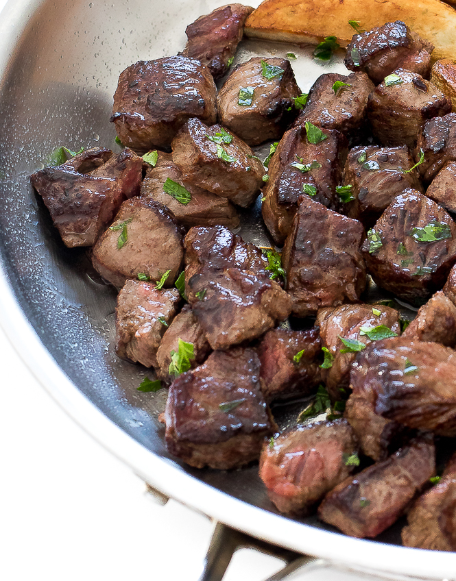 Garlic Herb Butter Steak Bites and Potato Wedges | chefsavvy.com Garlic Butter Steak Bites and Potatoes in a skillet.