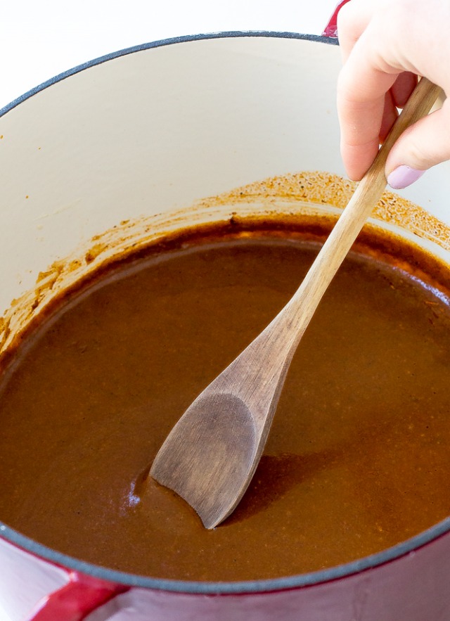 Stirring enchilada sauce with a wooden spoon.