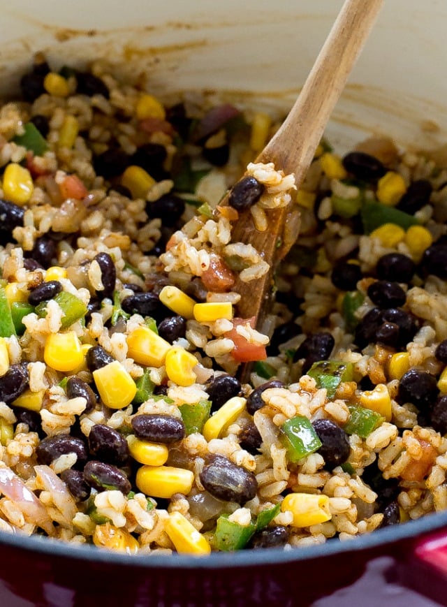 Stirring enchilada rice with a wooden spoon.