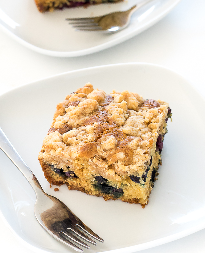 Sour Cream Coffee Cake | chefsavvy.com A slice of Blueberry and Sour Cream Coffee Cake on a white plate with a fork.