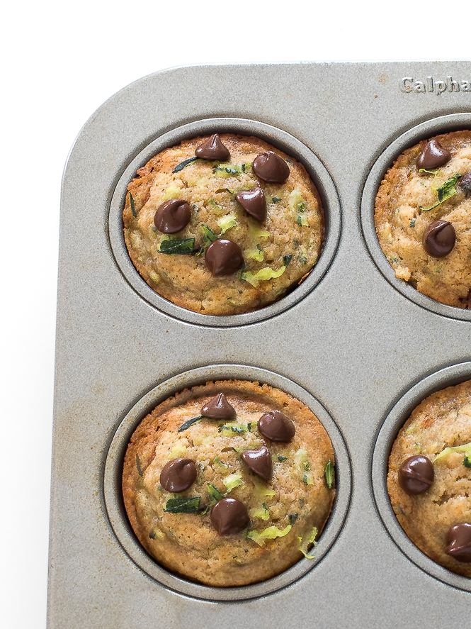 zucchini muffins in a muffin tin topped with chocolate chips