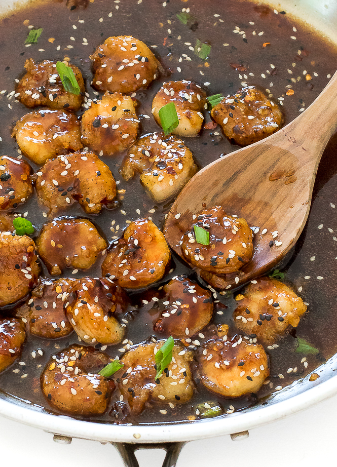 Teriyaki shrimp with green onion and sesame seeds in pan. 