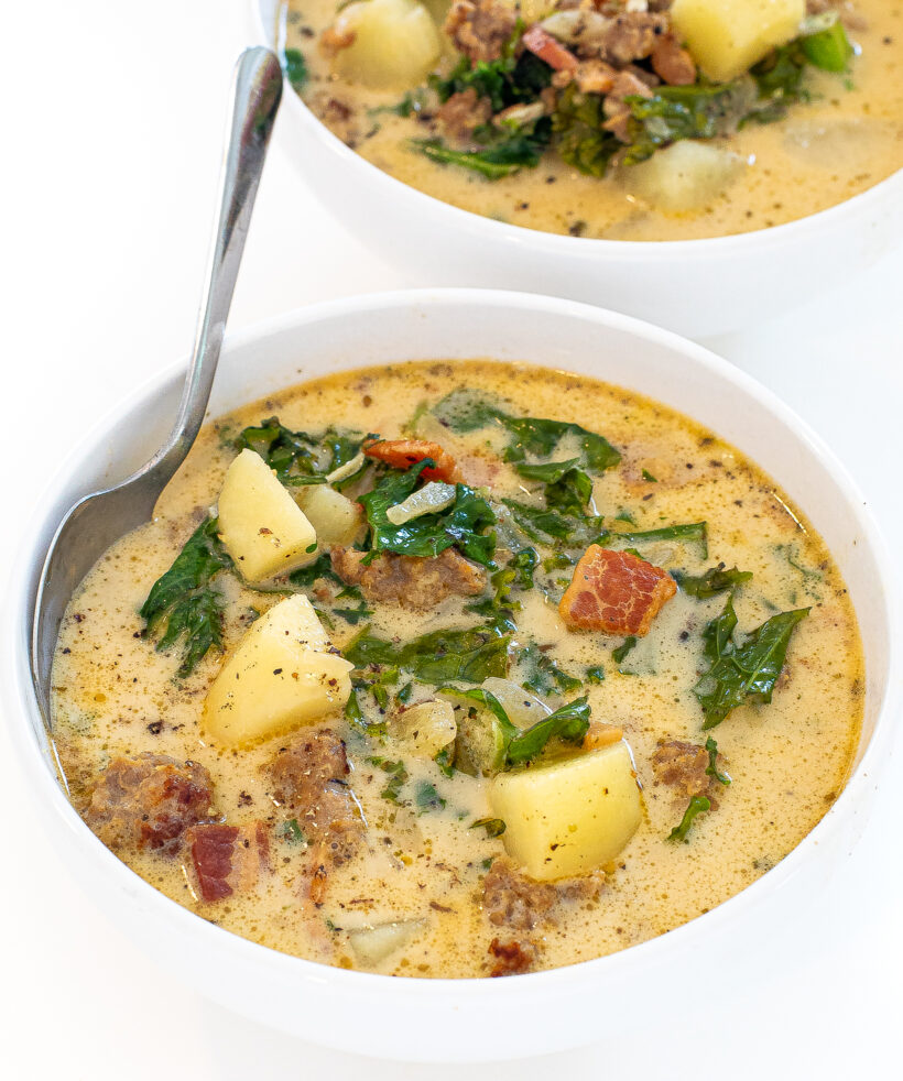Two bowls of zuppa toscana with a spoon in the bowl. 