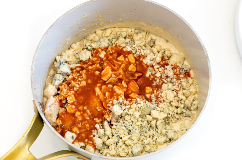 Blue cheese, shredded chicken, and buffalo sauce added to the saucepan.