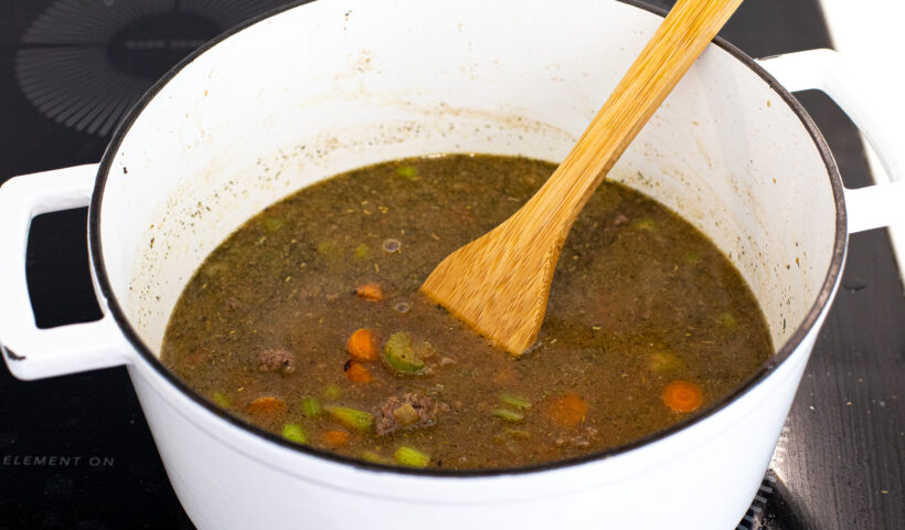 Soup in a pot with a wooden spoon to stir.