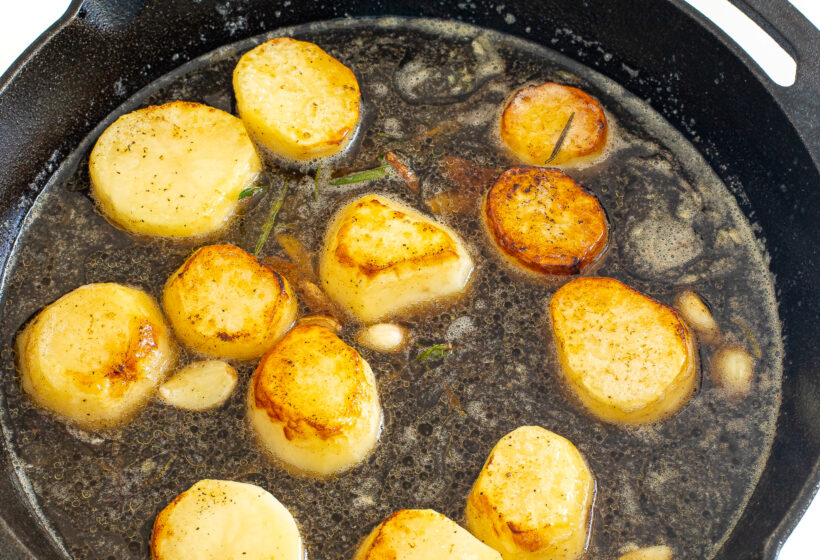Seared potatoes in a cast iron skillet with garlic and rosemary. 