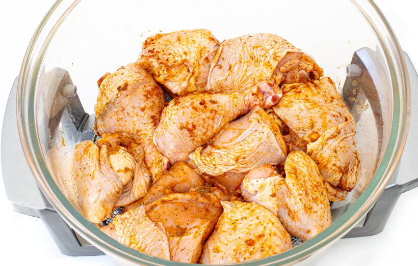 Pieces of chicken arranged in the basket of an air fryer. 