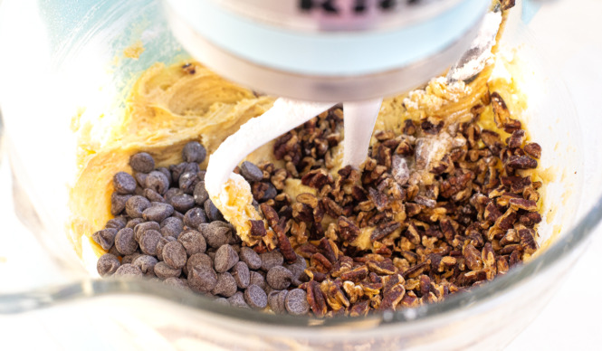 adding chocolate chips and pecans to stand mixer with the paddle attachment