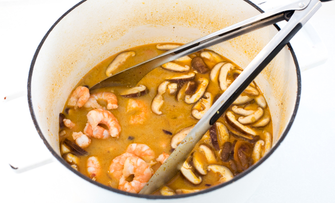 adding cooked shrimp, mushrooms. broth and coconut milk to pot