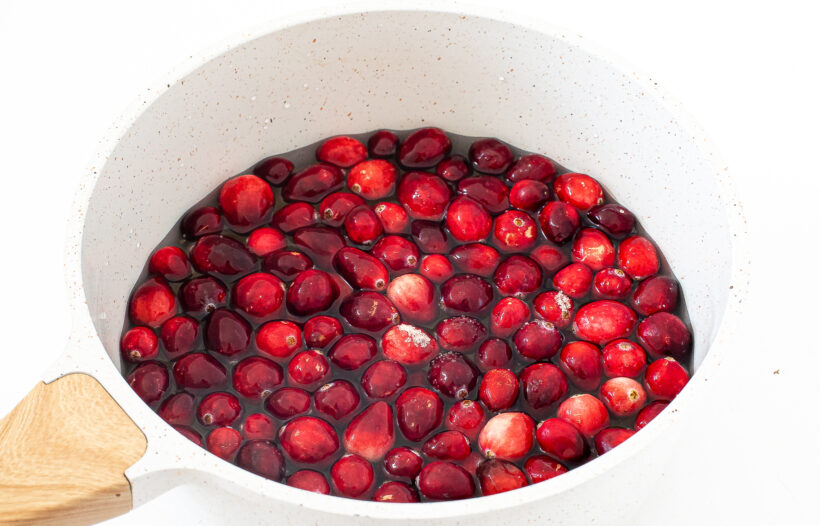 adding fresh cranberries, water and sugar to saucepan