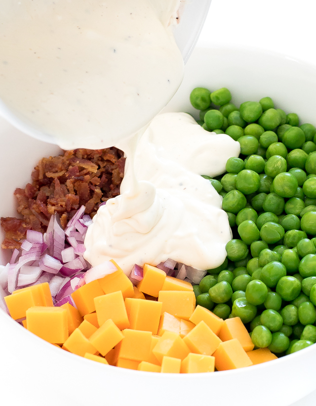 pouring dressing onto pea salad ingredients