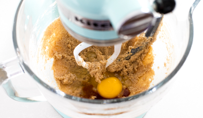 raw chocolate chip oatmeal cookie dough in the glass bowl of a stand mixer