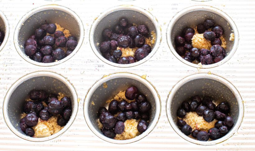 Blueberries added into the sugar and butter in the muffin tin. 