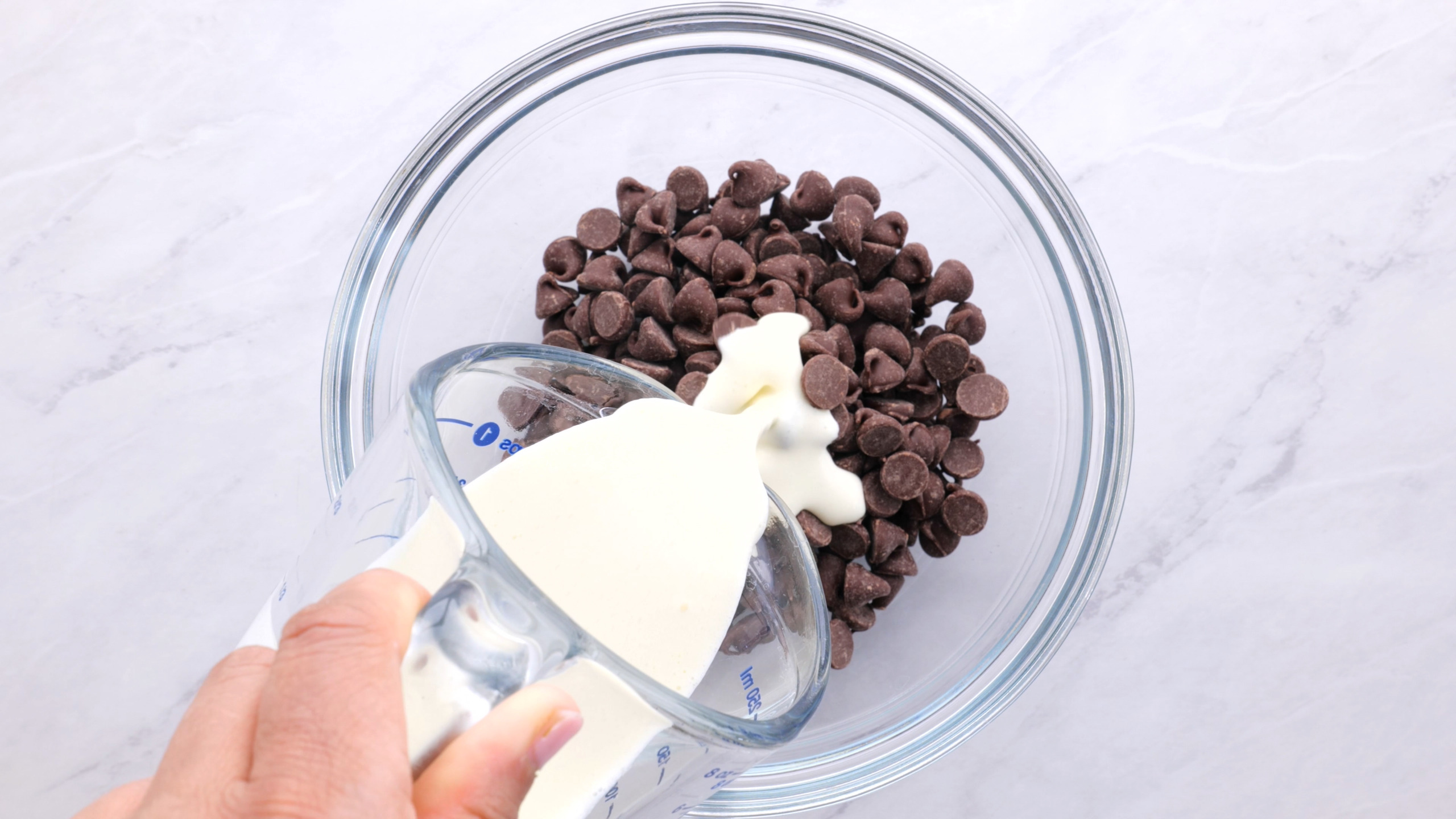 pouring heavy cream into bowl with semi sweet chocolate chips
