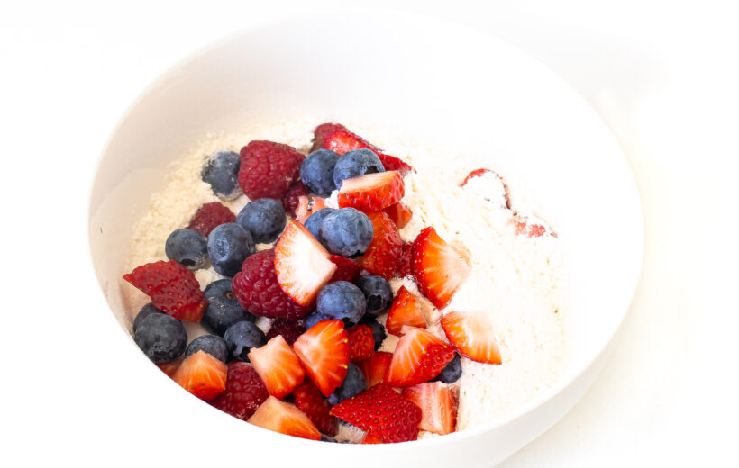 Fruit being coated in flour in a bowl.