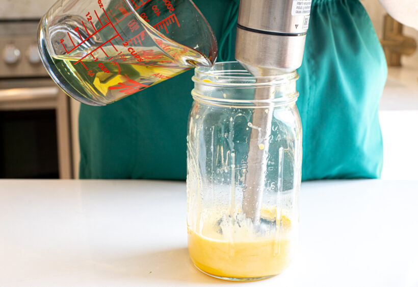 Pouring avocado oil into jar with homemade mayo.