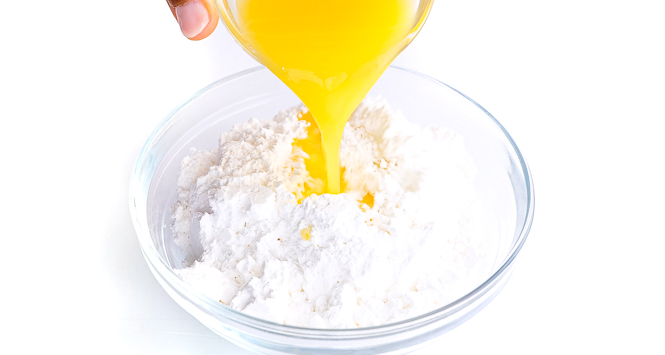 pouring orange juice with powdered sugar in a small bowl