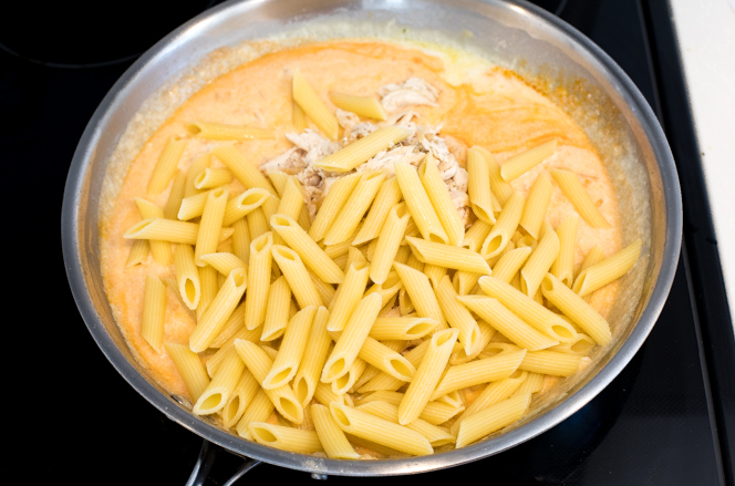 Adding cooked pasta and chicken to cheese sauce Adding cooked pasta and chicken to cheese sauce