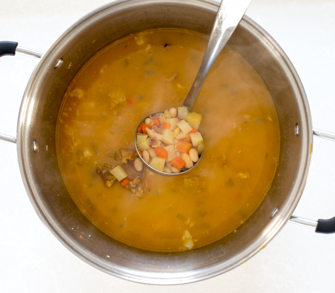 simmered ham and bean soup in large pot with ladle