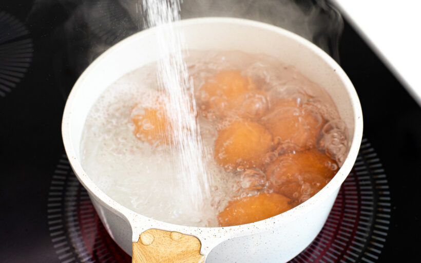 Salt being poured into a pot of boiling eggs.
