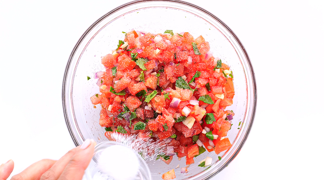 adding salt to Pico de Gallo in small clear bowl