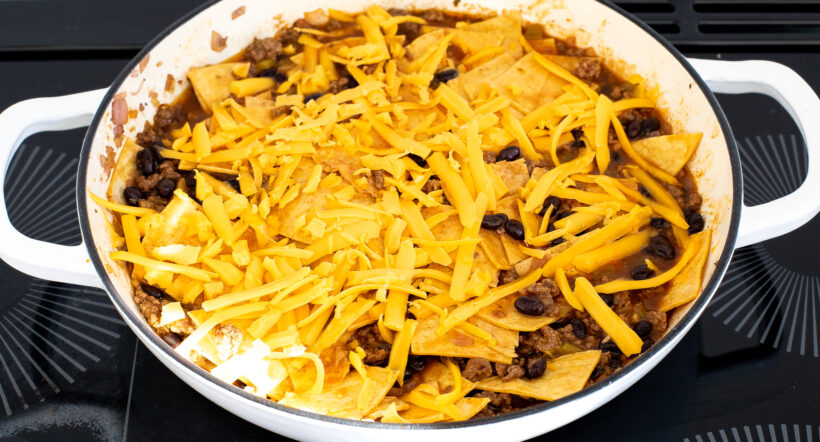 Skillet beef enchiladas with cheese on top before being baked. 