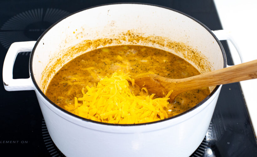 Shredded cheddar cheese being added to the soup.