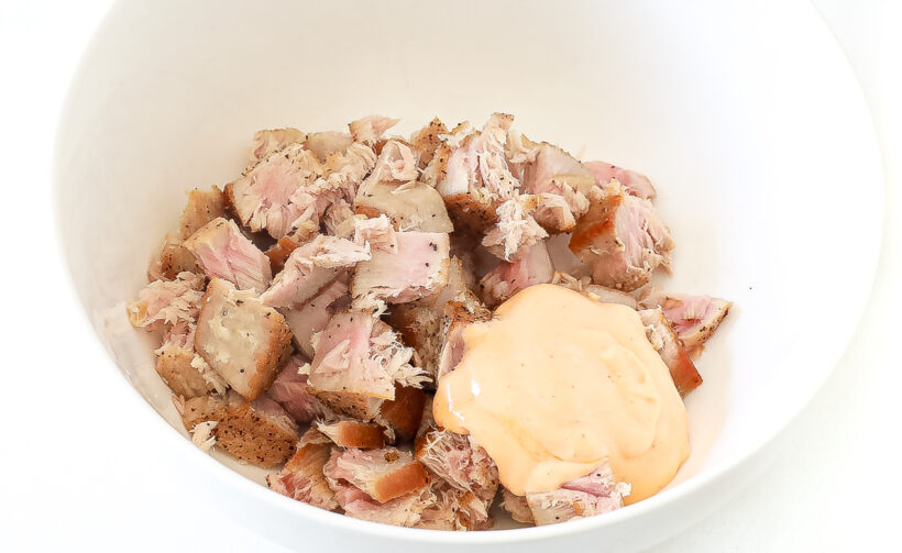 Seared tuna in small cubes in a bowl with spicy mayo.