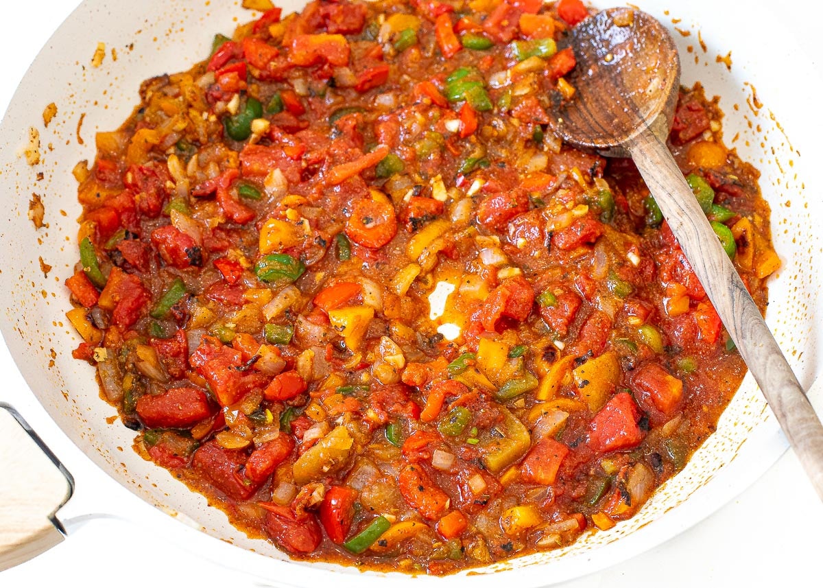 adding fire roasted tomatoes to pan with sautéed vegetables