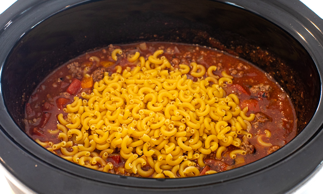 Tomato sauce & ground beef with uncooked noodles on top in a crockpot. 