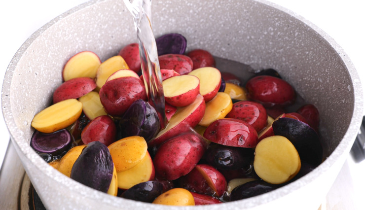 pouring water over baby potatoes in small pot