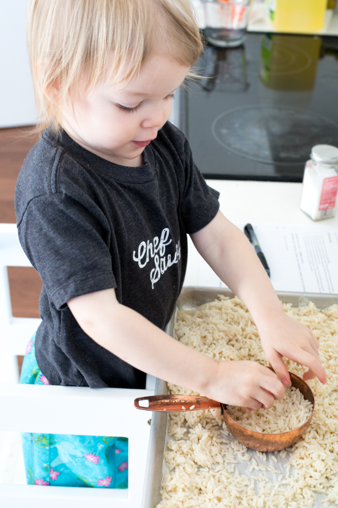 Toddler breaking up rice in a kitchen