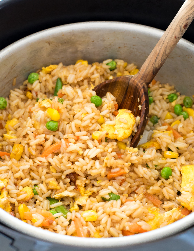 Rice in a pot being stirred with a wooden spoon.