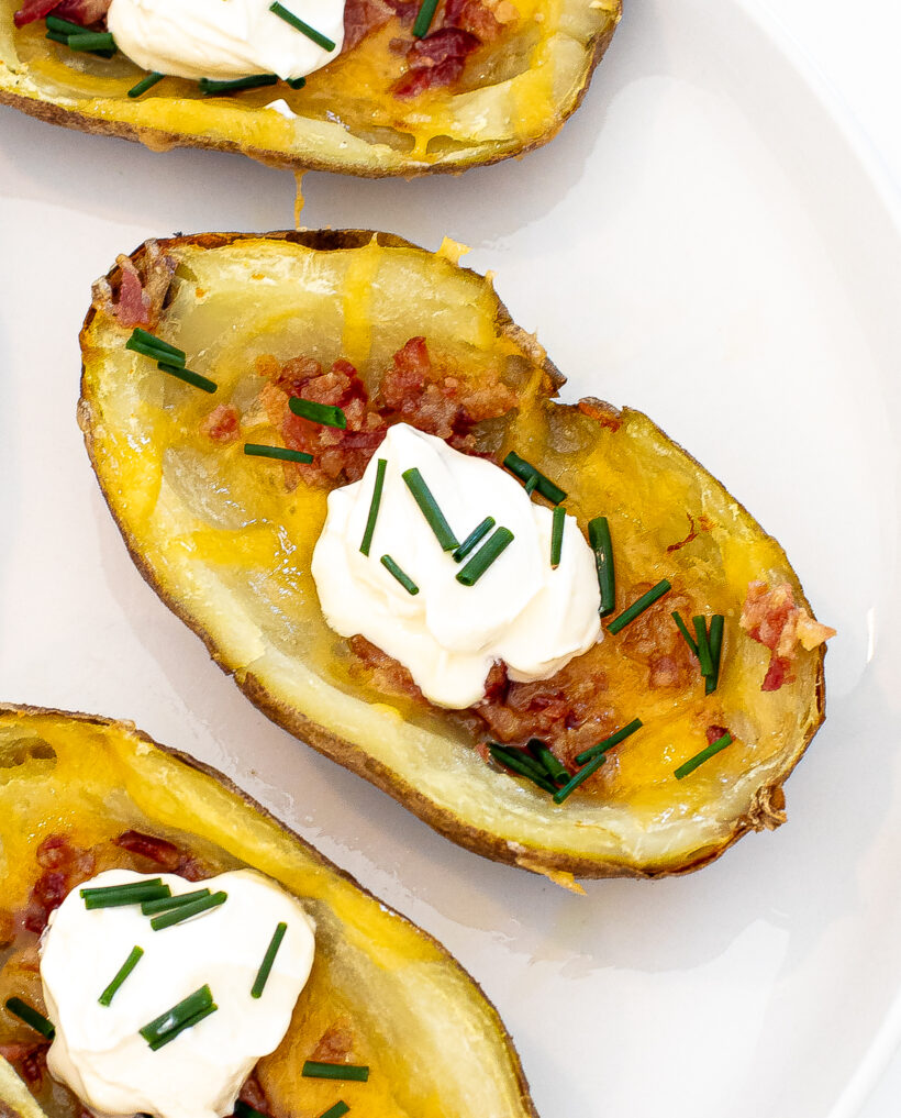 Up close shot of potato skin with cheese, bacon, sour cream and chives. 