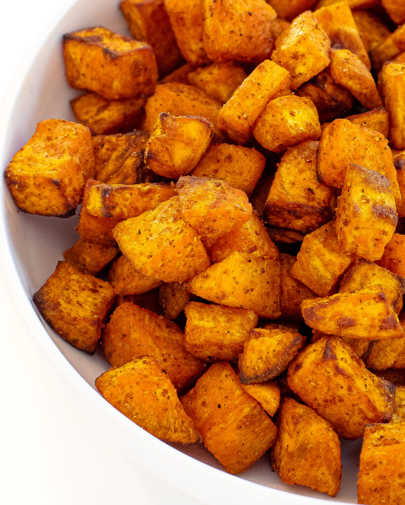 Sweet potato chunks after being roasted in a white serving bowl.