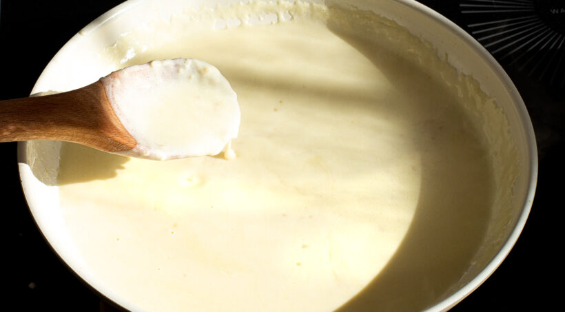 Alfredo sauce simmering in a skillet on the stove. 