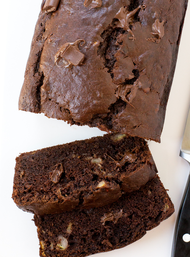Easy Double Chocolate Banana Bread | chefsavvy.com Double Chocolate Banana Bread sliced on a white board next to a knife.
